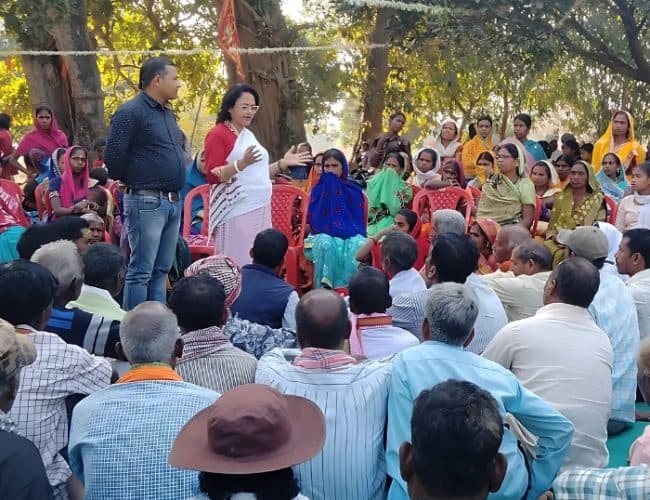 A woman speaking with village residents gathered outdoors